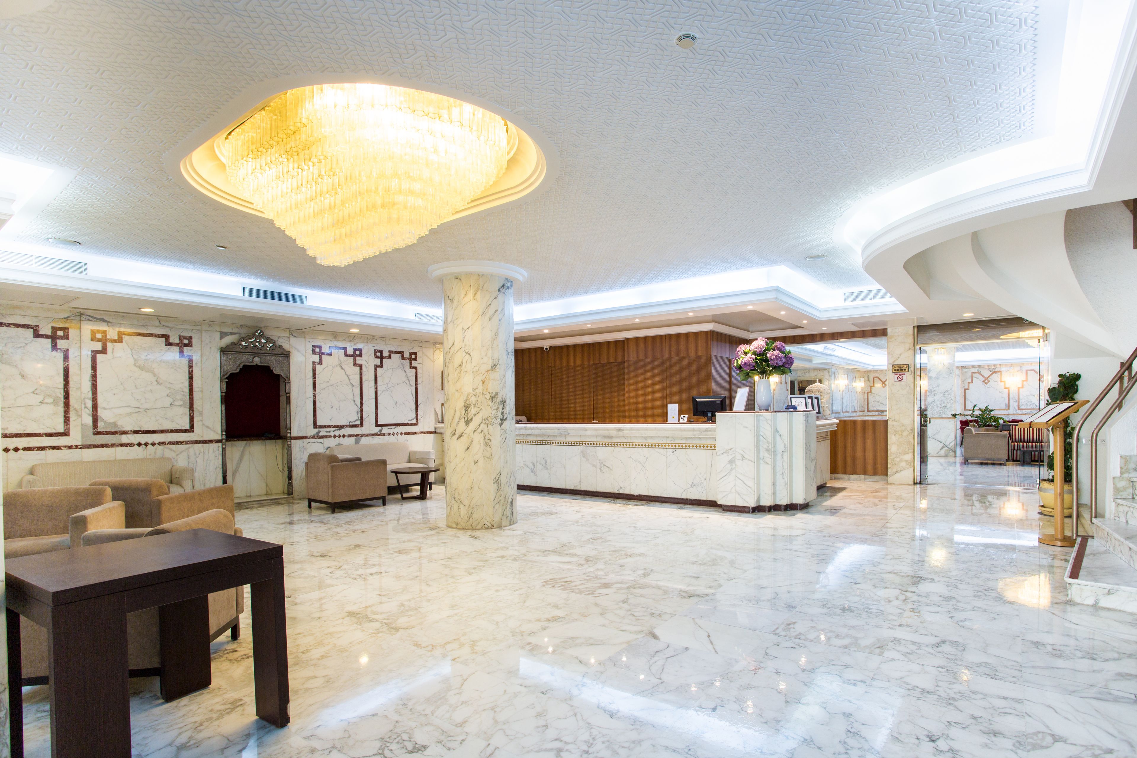 Um hall amplo com piso de mármore, um lustre grande e um balcão de recepção.