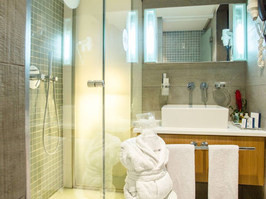 A modern bathroom with a glass shower enclosure, a white sink, and a wooden vanity.