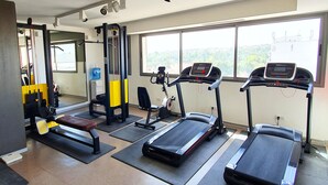 Un gimnasio con cintas de correr, una prensa de banca y una estructura para sentadillas.