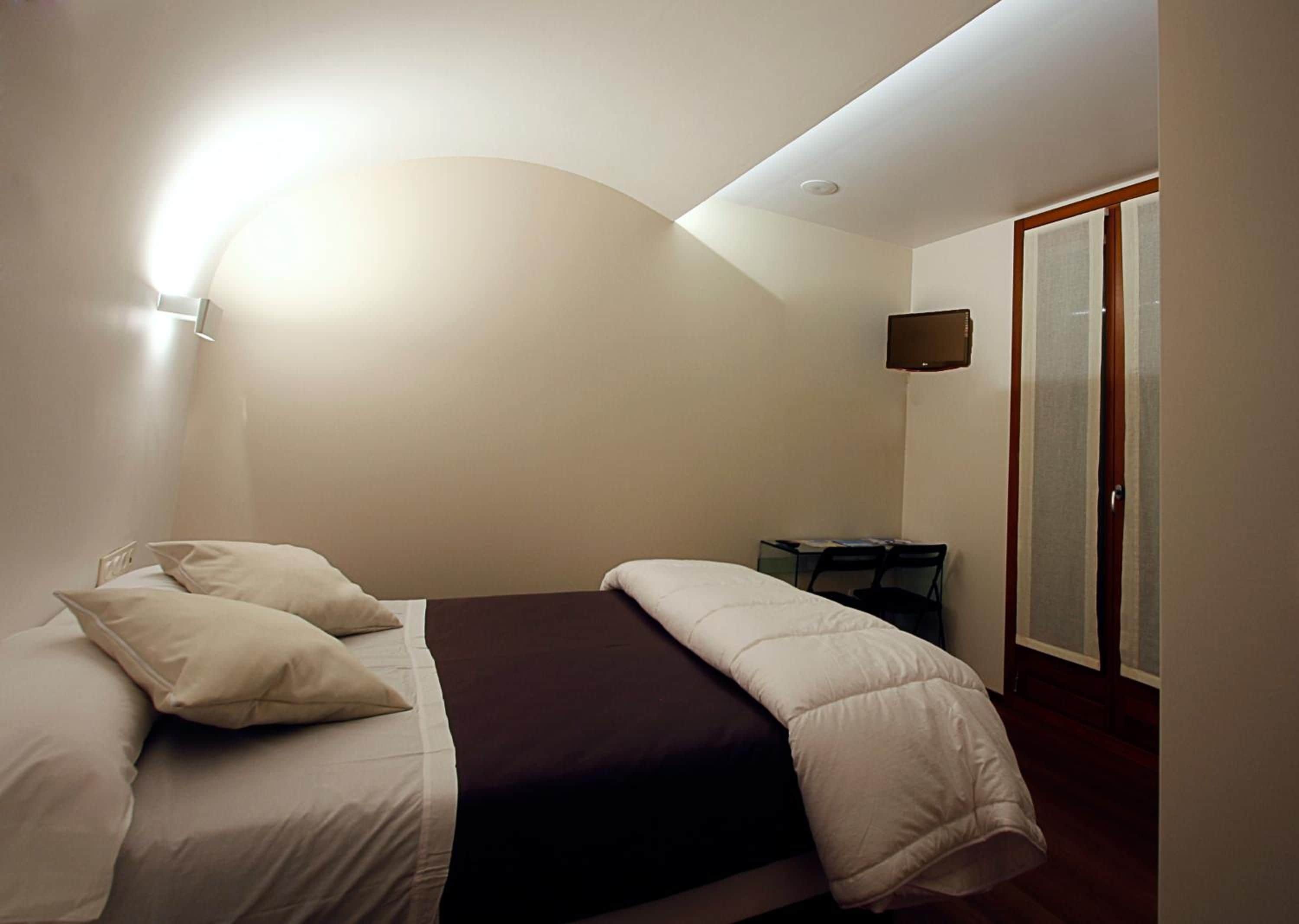 Un dormitorio con cama, almohadas, un escritorio y una silla.
