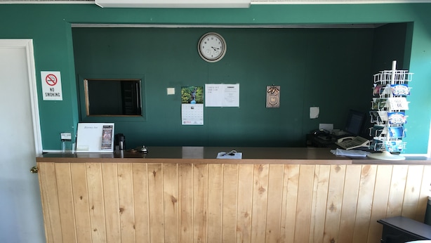 A reception desk with a clock, no smoking sign, and a calendar on the wall. - Blarney Inn (Shamrock)