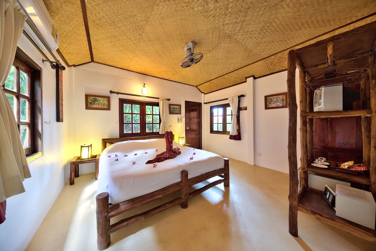 A spacious room with a wooden bed, a ceiling fan, and a wooden cabinet with a television.