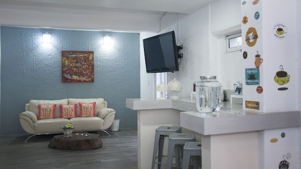 A modern living room with a sofa, a coffee bar, and a TV mounted on the wall. - Hotel Karenina (Oaxaca)