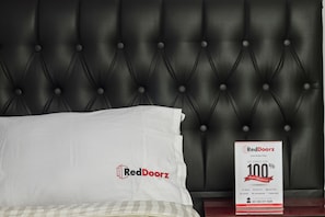 A bed with a white pillow and a RedDoorz sign on the headboard. - RedDoorz Plus @ Guntur Raya Setiabudi (Jakarta)