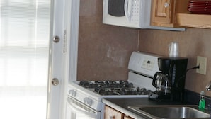 A kitchen with wooden cabinets, a white stove, a microwave, and a coffee maker.