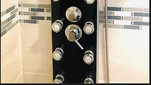 A shower with multiple controls and a handheld showerhead.