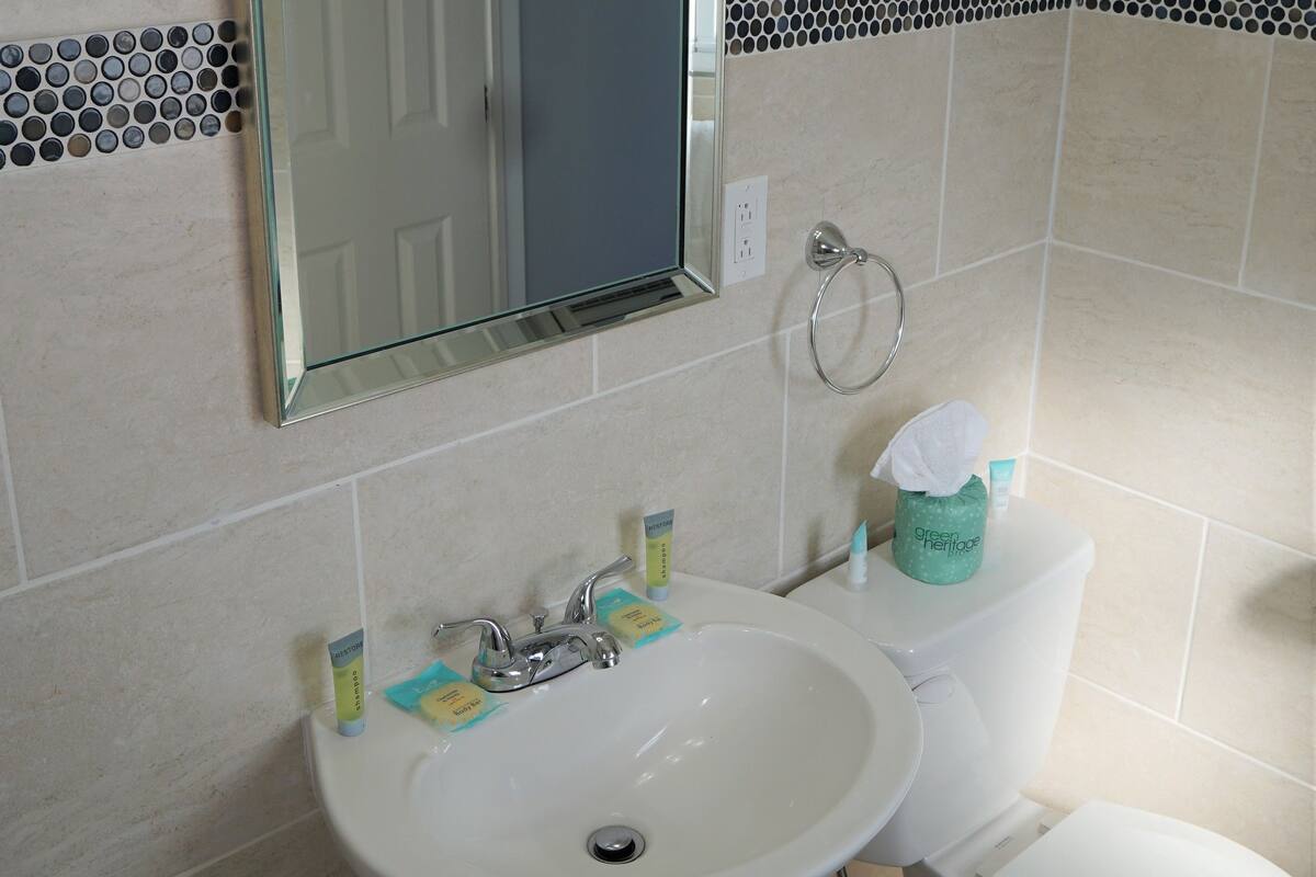 Un baño con lavamanos blanco, un espejo y un inodoro.