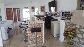 Cozinha moderna com parede de pedra, geladeira e bancada com banquetas.