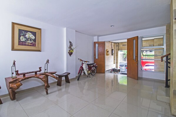 Una habitación amplia con un banco de madera, un patinete rojo y una puerta que da al exterior.