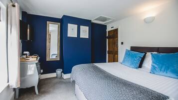 Une chambre à coucher avec un lit, une table de chevet, un miroir et une porte.