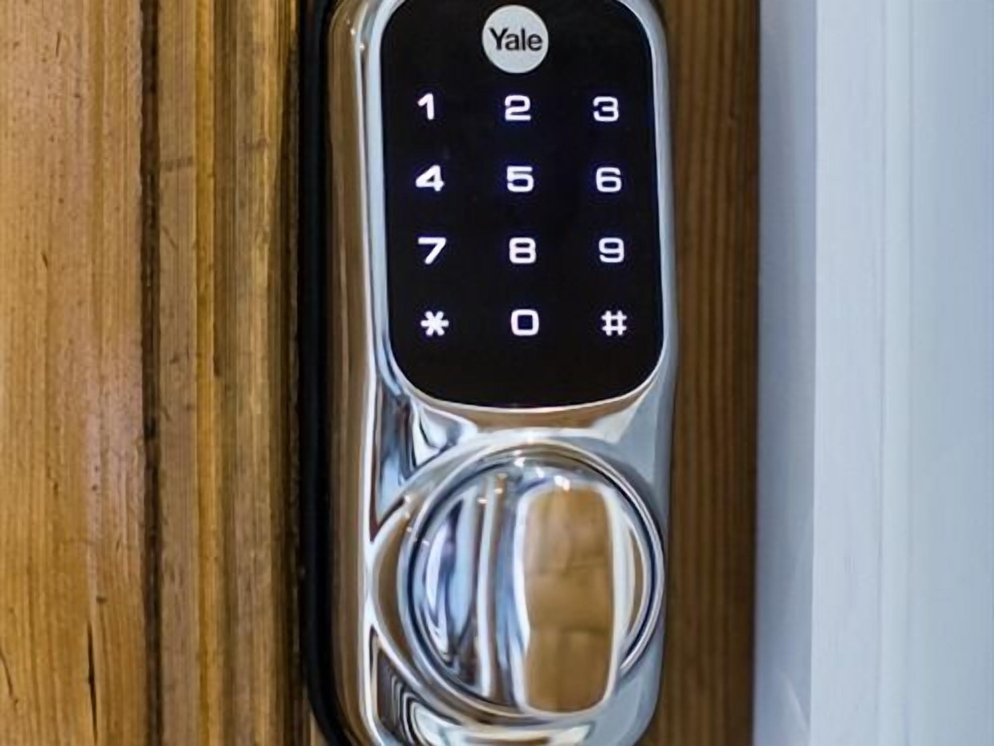 A Yale keypad lock on a wooden door.