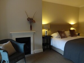Relax in a classic room with a large bed, nightstands, and a comfortable armchair.