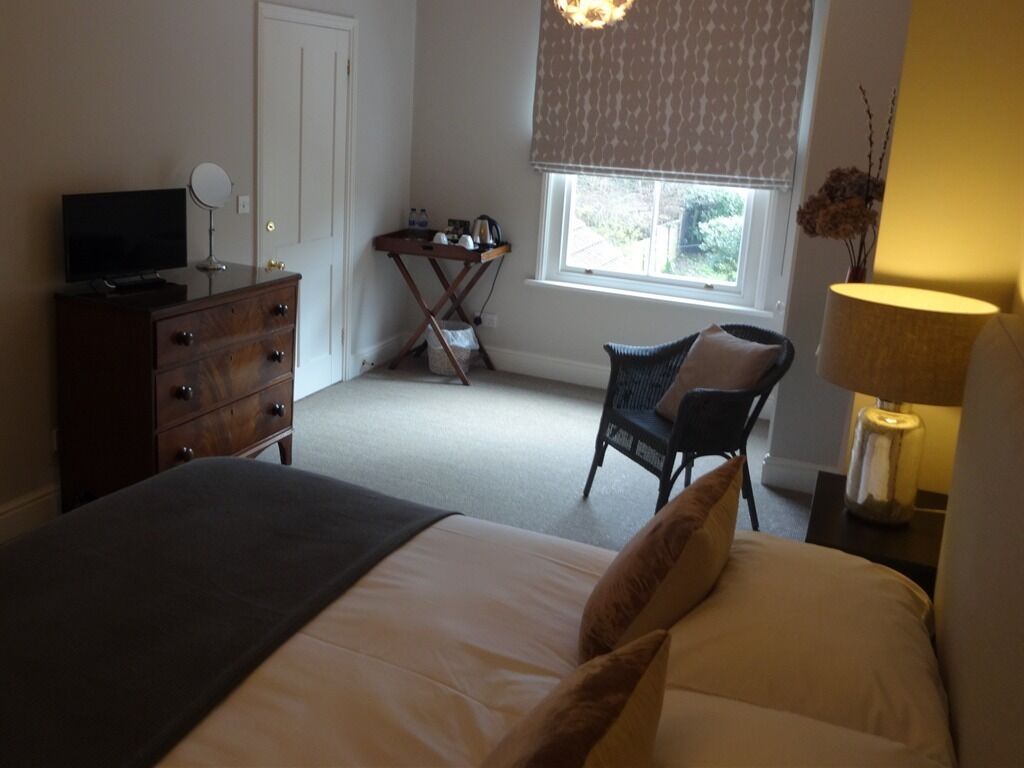A bedroom with a bed, dresser, chair, and a desk with a lamp.