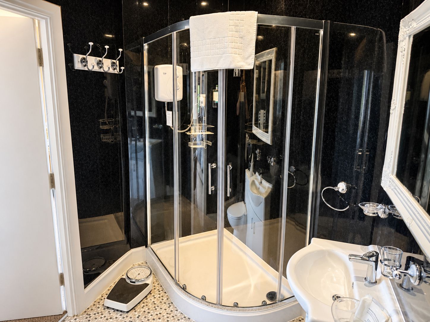 A modern bathroom with a glass-enclosed shower, a white sink, and a large mirror.