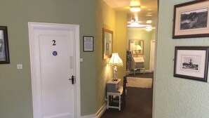 A hallway with a white door marked with the number 2, a small table with a lamp, and framed pictures on the walls. - The Stockton Arms (Stockton-on-Tees)