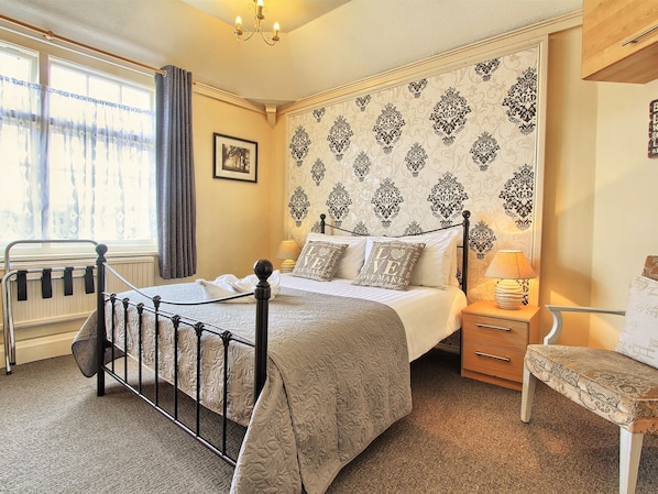 A neatly arranged bedroom with a bed, bedside lamp, chair, and a window with curtains. - The Stockton Arms (Stockton-on-Tees)