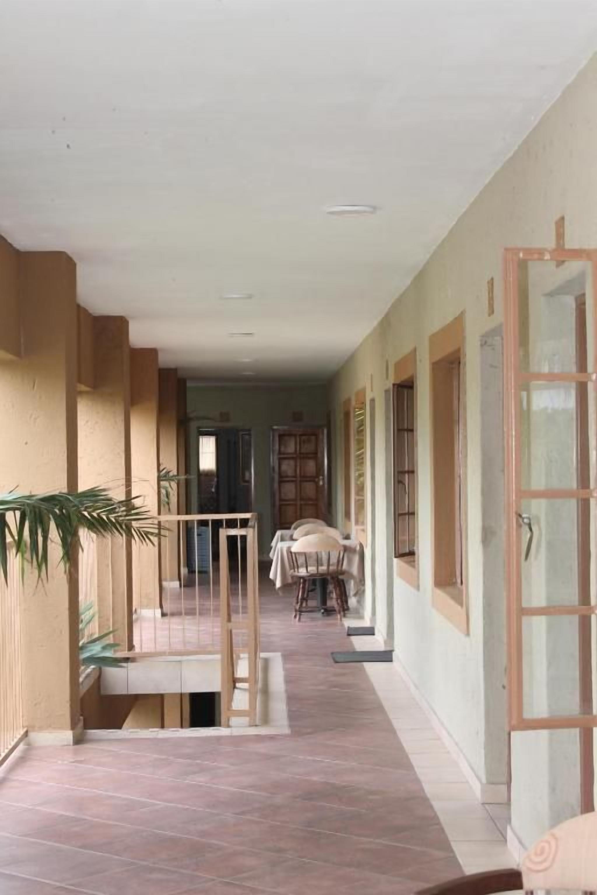 A corridor with a dining area, a staircase, and a door with a glass panel.