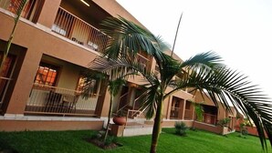 A modern building with multiple balconies, palm trees, and a well-maintained lawn.