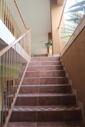 A staircase with wooden railings and red-tiled steps leading to a landing.