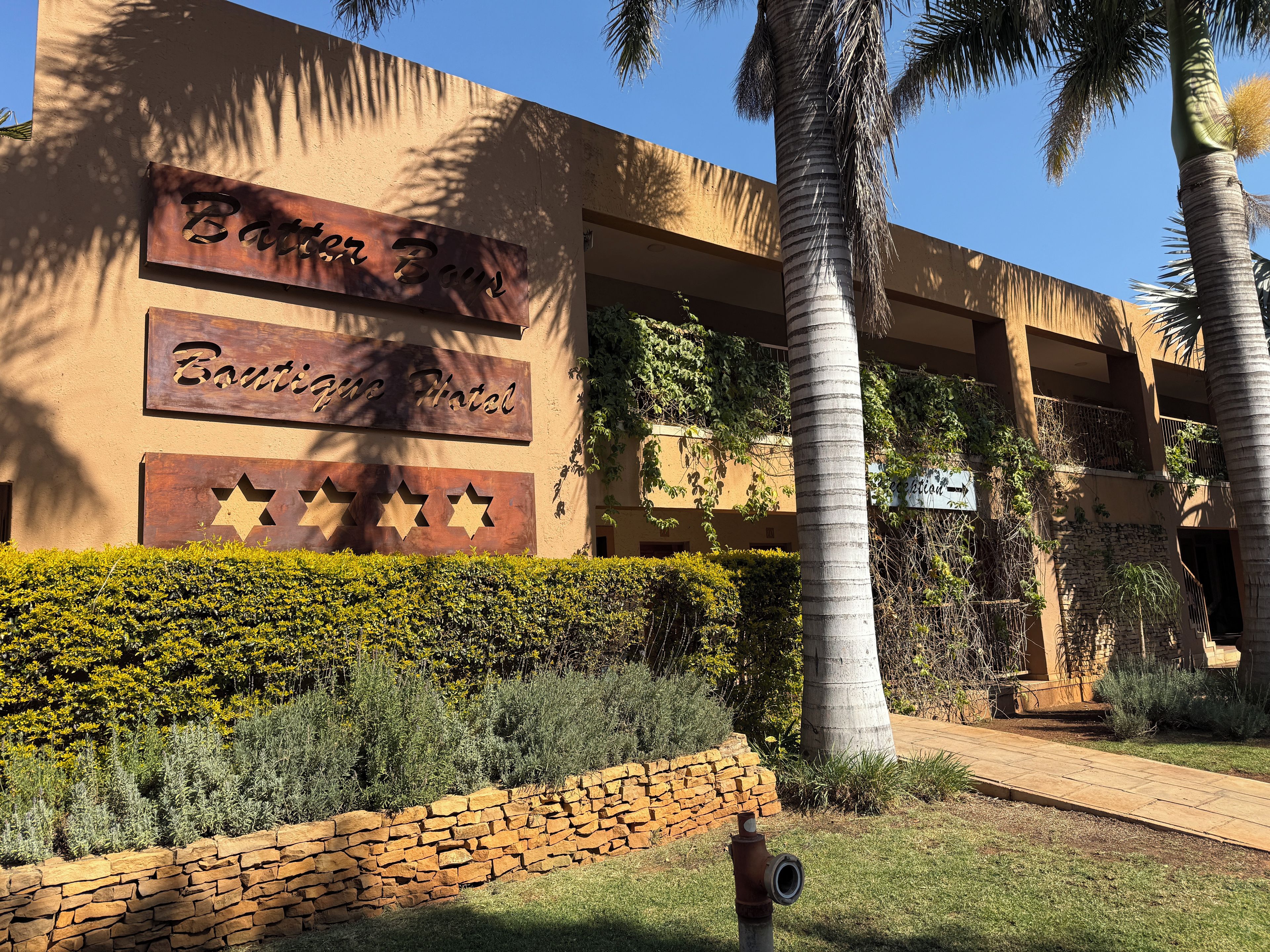 A building with a sign reading 'Boutique Hotel' and a stone wall with a star design.
