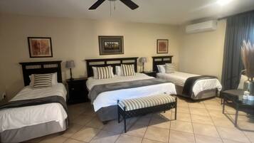 A hotel room with three beds, a ceiling fan, and a nightstand with a lamp.