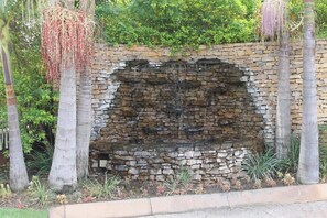 A stone waterfall feature surrounded by palm trees and greenery.