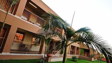 A multi-story building with balconies, a well-maintained lawn, and palm trees.