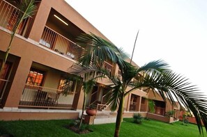 A multi-story building with balconies, a well-maintained lawn, and palm trees. - Batter Boys Boutique Hotel (Pretoria)