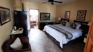 A hotel room with a bed, a desk, a chair, a television, and a ceiling fan.