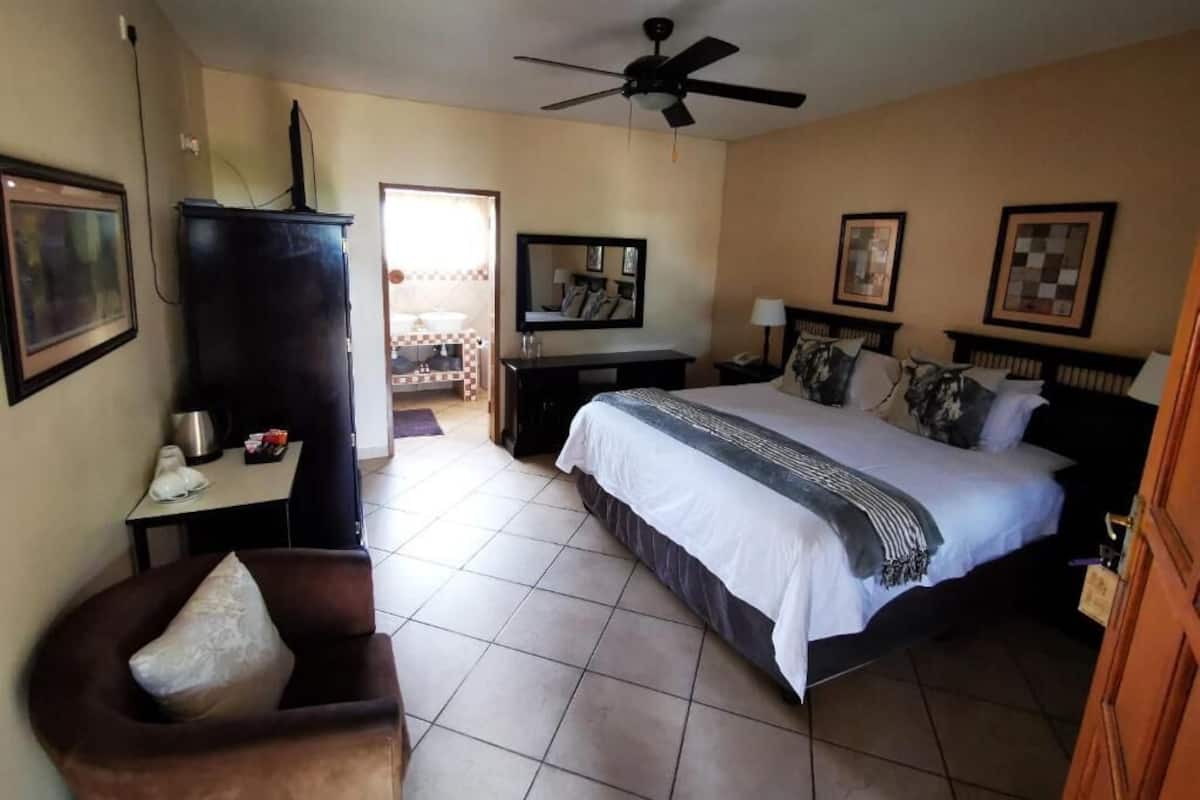Une chambre d’hôtel équipée d’un lit, d’un bureau, d’une chaise, d’une télévision et d’un ventilateur de plafond.