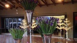 A buffet table with various food items and decorative flowers.