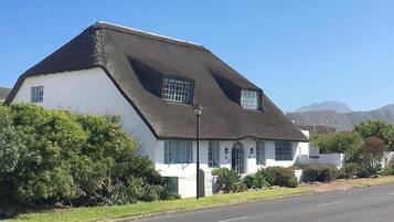 A white building with a black roof, a small window, and a lamp post.