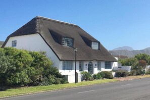 A white building with a black roof, a small window, and a lamp post.
