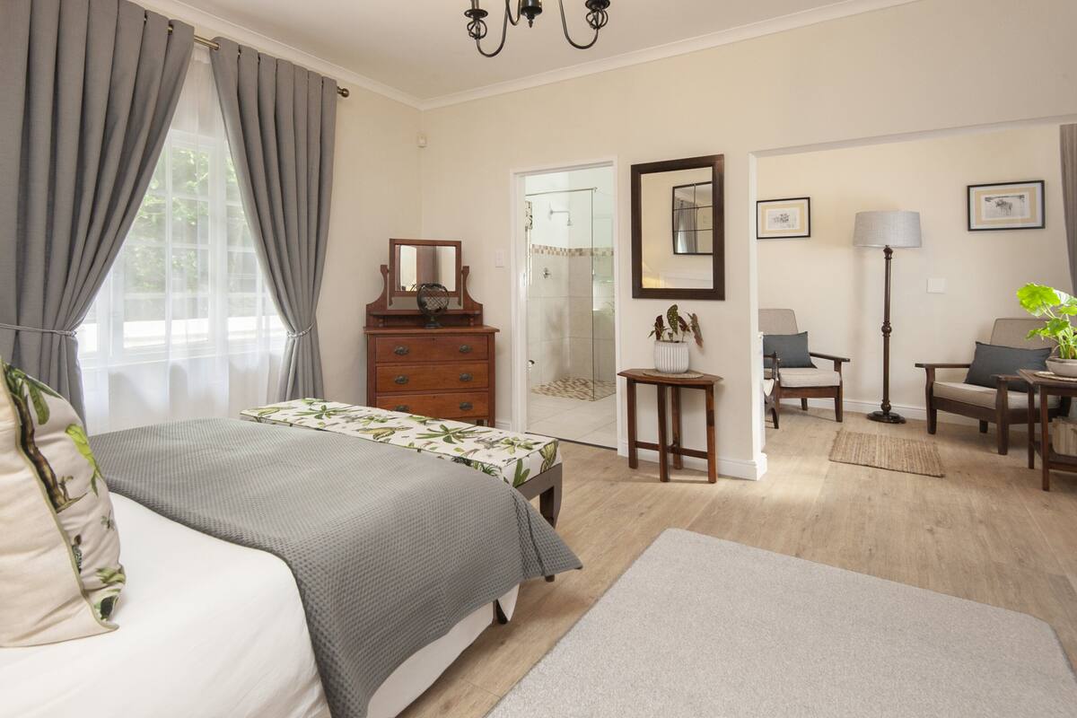 Quarto com cama, penteadeira e uma mesinha de cabeceira com abajur.