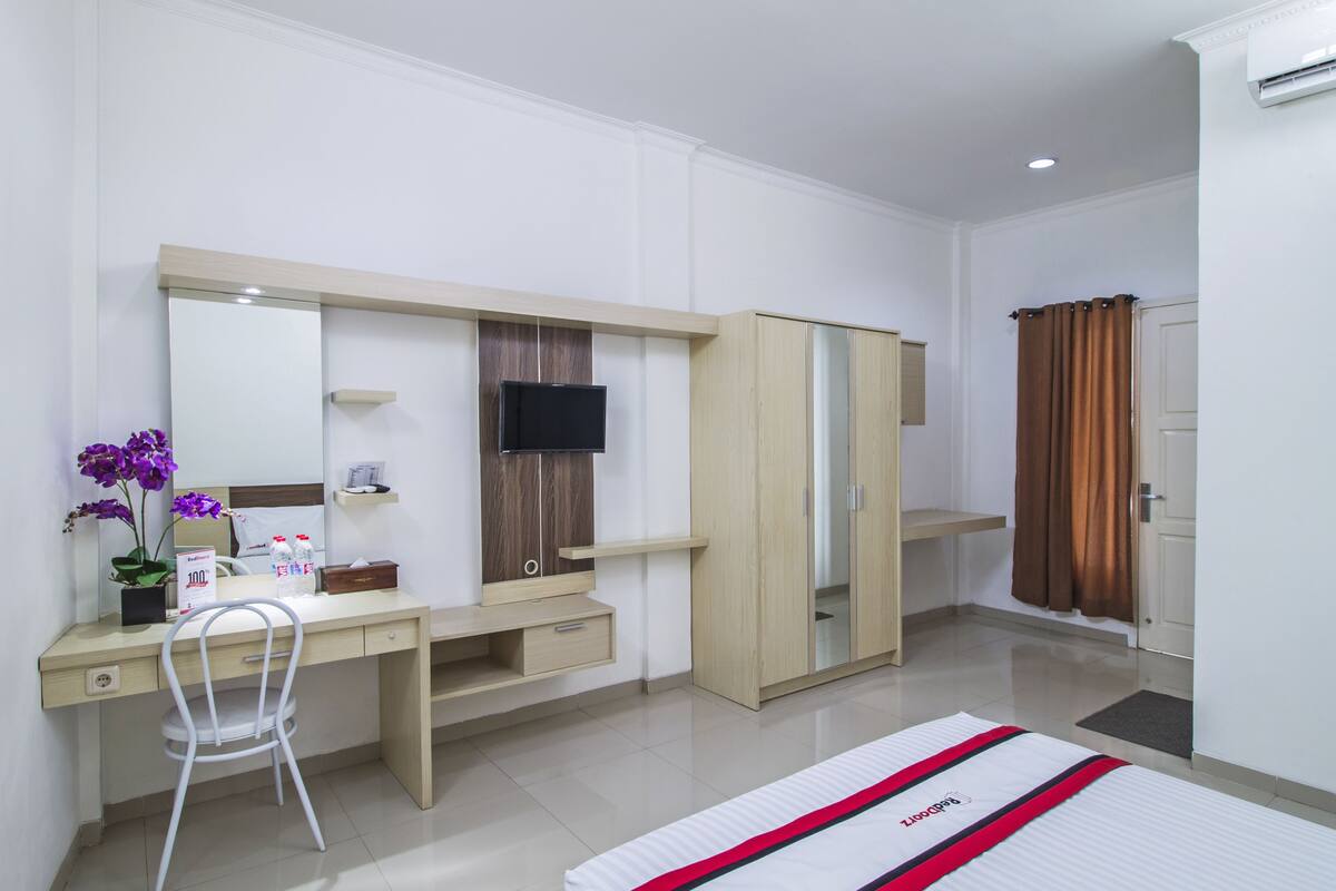 Un dormitorio moderno con cama, escritorio, silla, armario y televisor.