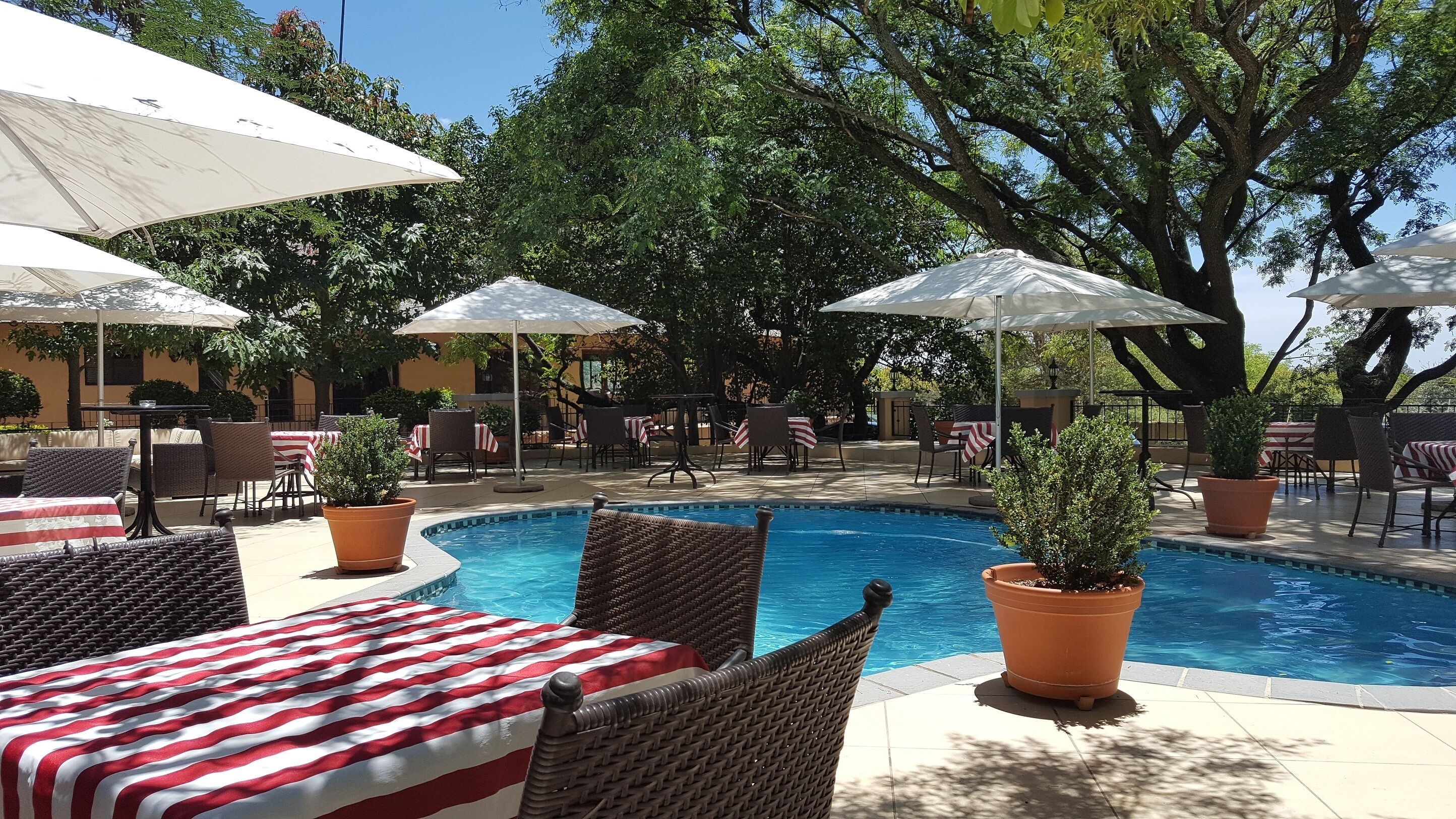 Un espace aménagé au bord de la piscine, avec des chaises longues, des parasols et des tables.