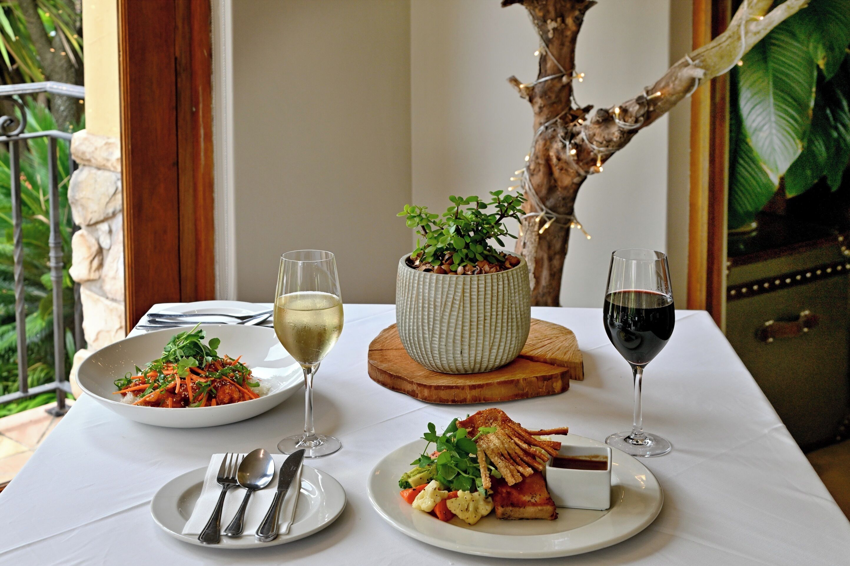 A dining table with plates of food, glasses of wine, and cutlery.