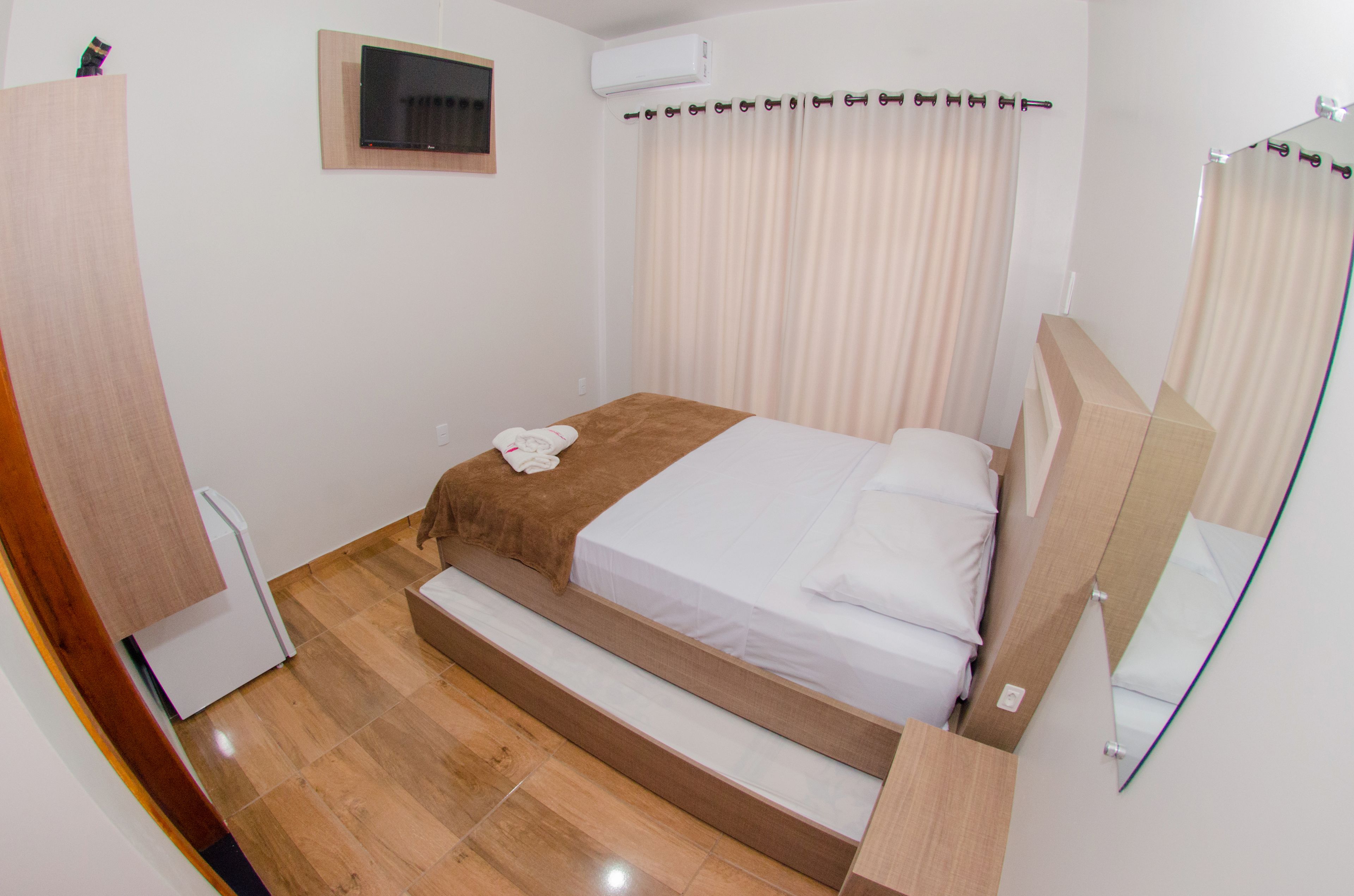 Een slaapkamer met een bed, een klein raam, een airconditioner en een spiegel.