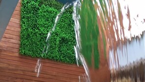 A pool with a water feature, two wicker chairs, and a small table with a bottle and glasses. - Pousada Rosa (Penha)