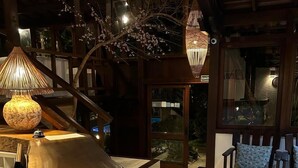 Ein modernes Interieur mit einer Holztreppe, einem Sofa, einem Tisch mit einem Glas und einer hängenden Leuchte.