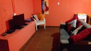 A living room with a television, a sofa, and a chair.