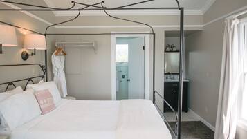 A bedroom with a four-poster bed, a walk-in closet, and a bathroom visible through an open door.