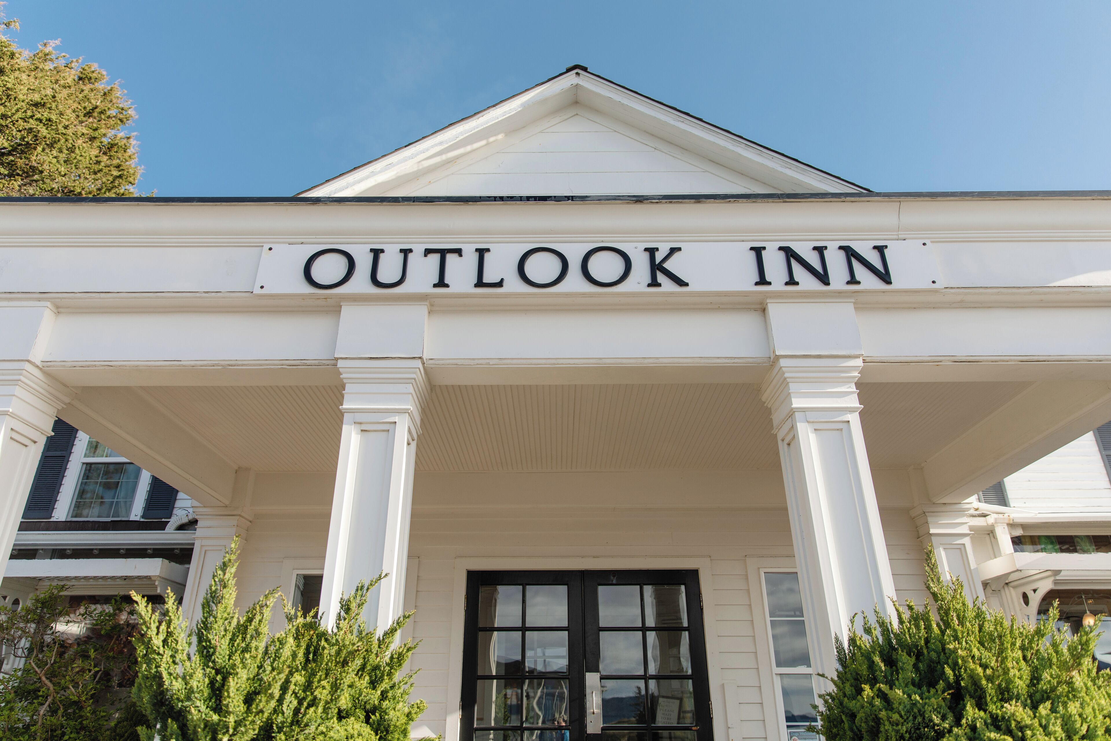 La entrada del Outlook Inn, con una fachada clásica blanca y ventanas de marco negro.
