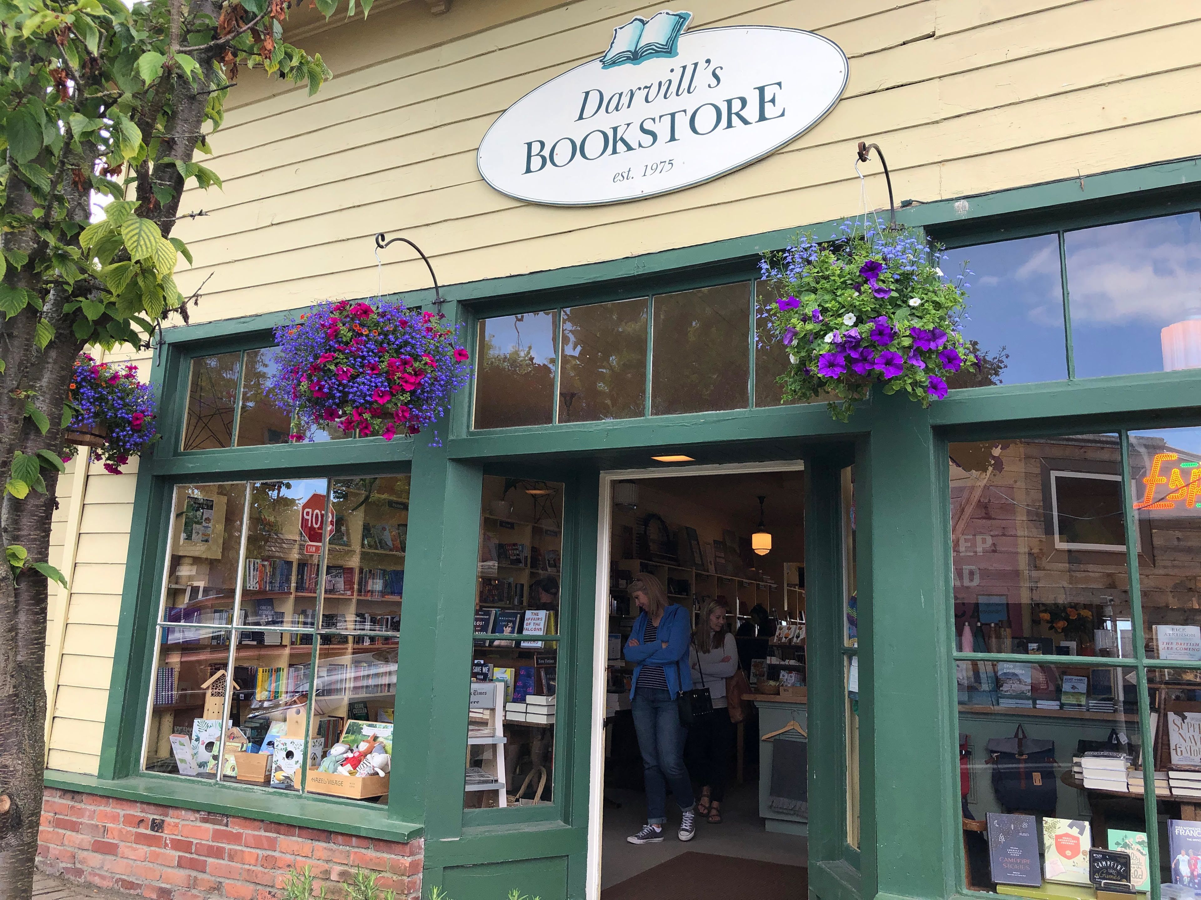 Librería Darvill's con fachada verde, amplias ventanas y macetas colgantes de flores.