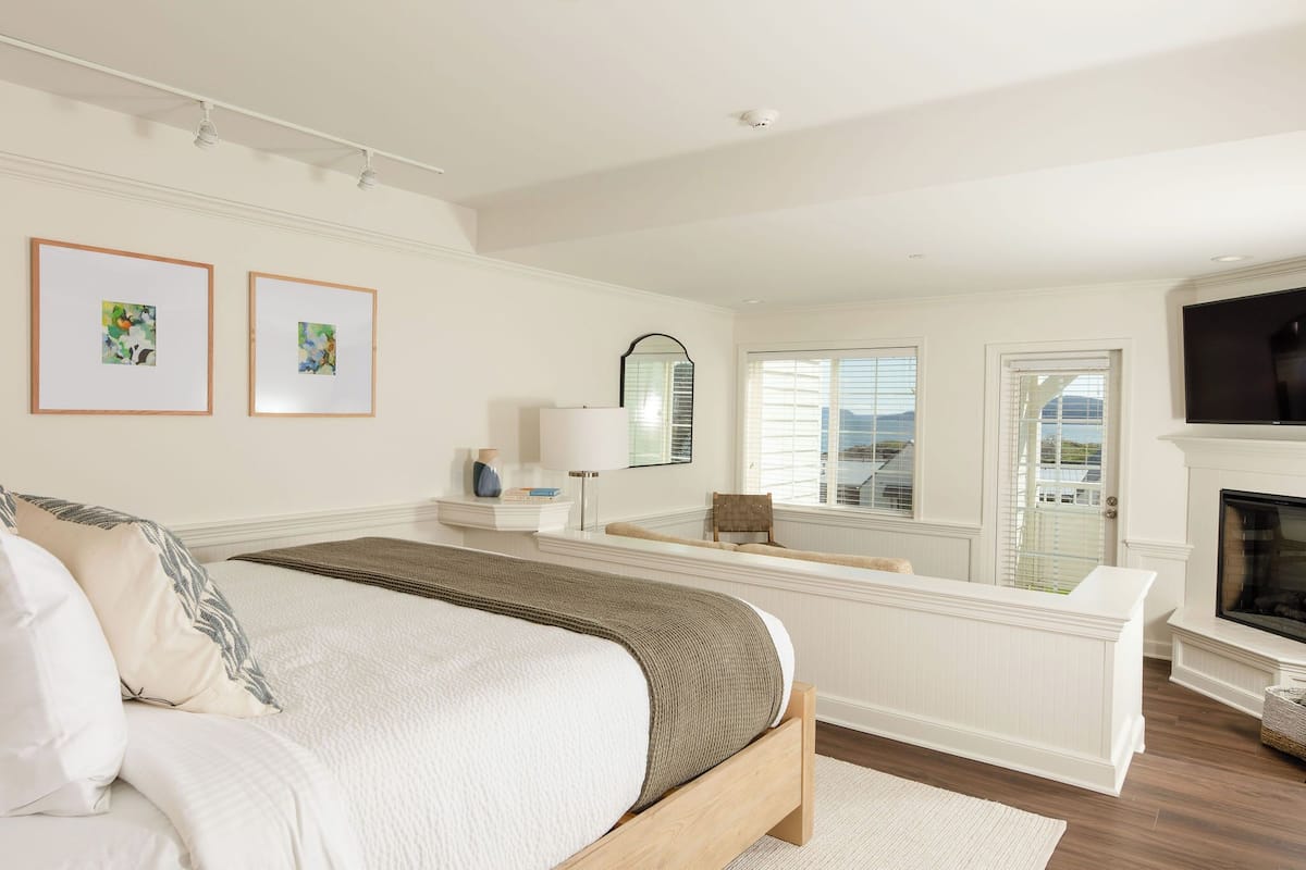 A bedroom with a large bed, a fireplace, and a view of the outside.