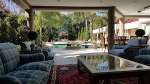 Ein Sitzbereich im Freien mit Karomöbeln, einem Tisch mit Glasplatte und einem Pool im Hintergrund.
