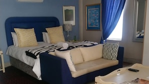 Ein Schlafzimmer mit Bett, Sofa, Couchtisch, Teppich und einem Fenster mit Vorhängen.