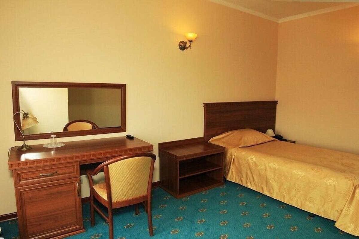 A hotel room with a wooden desk, chair, and bed.