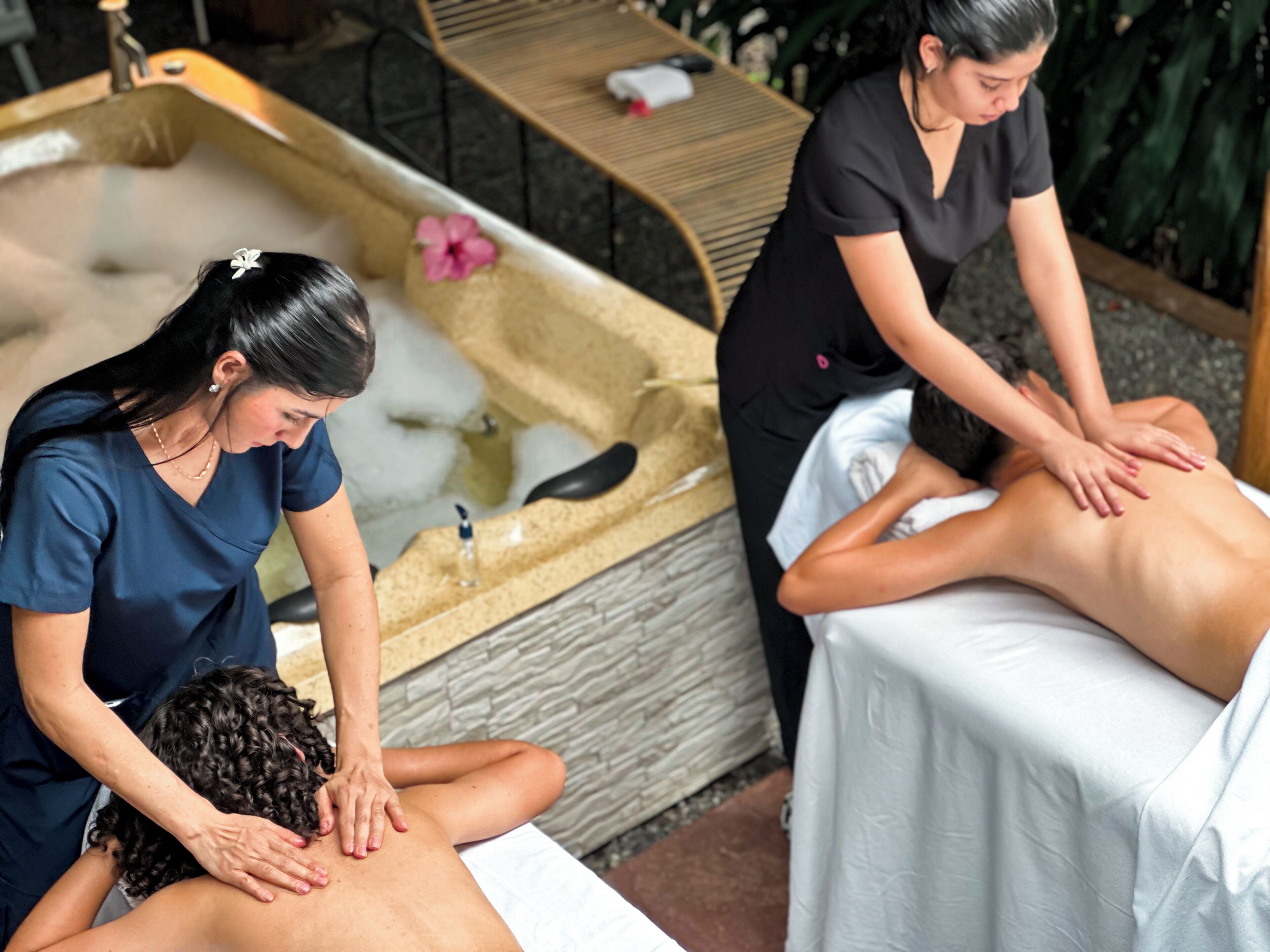 A spa setting with a massage area, a bathtub, and a wooden bench.