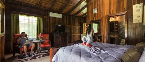 A wooden cabin room with a bed, a desk, and a chair.
